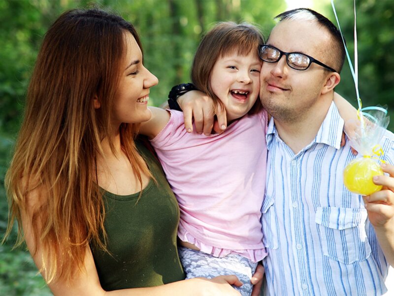 Family with young daughter smiling outdoors